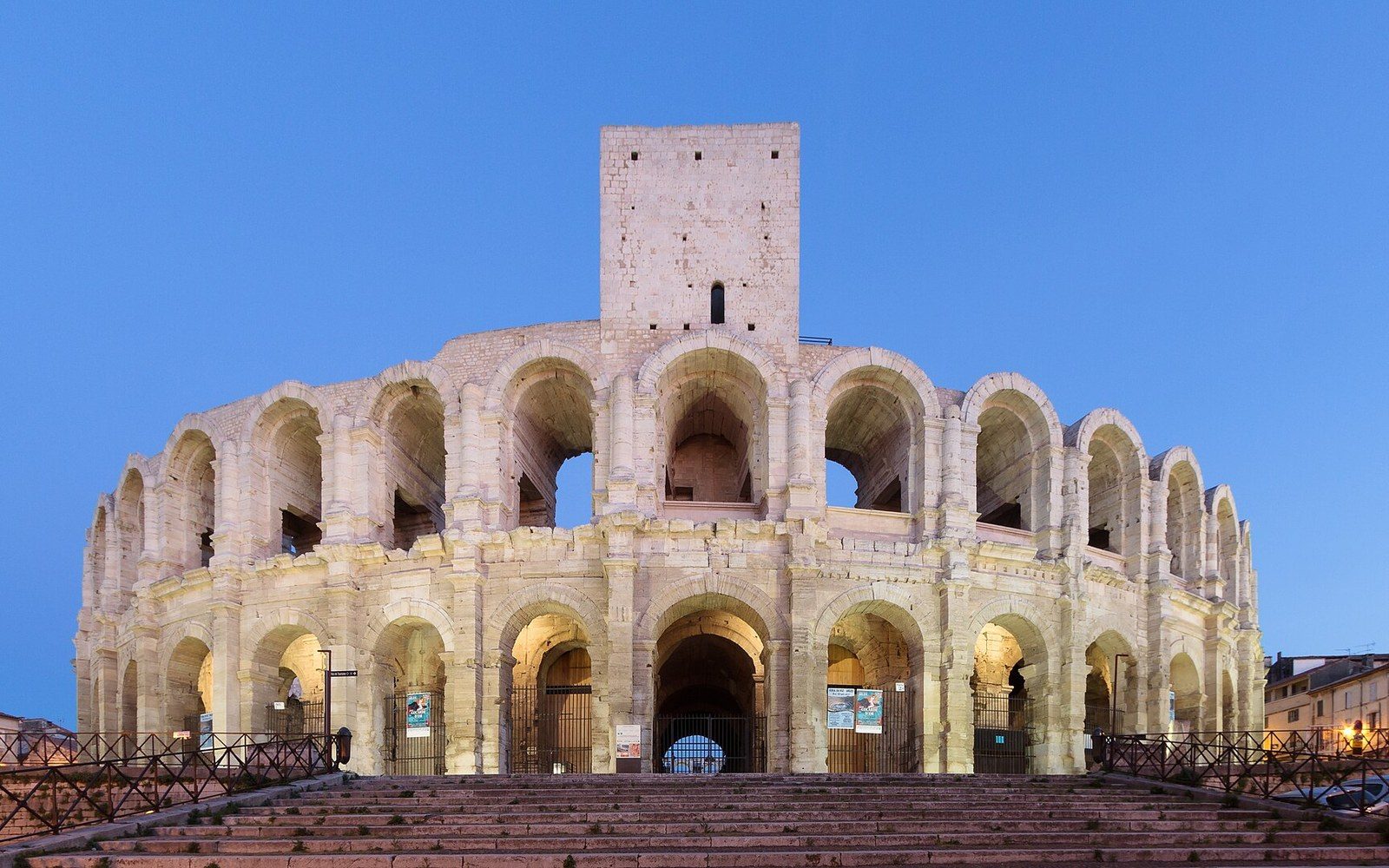 Roman amphitheatre in Arles with tiered stone arches lit at dusk
