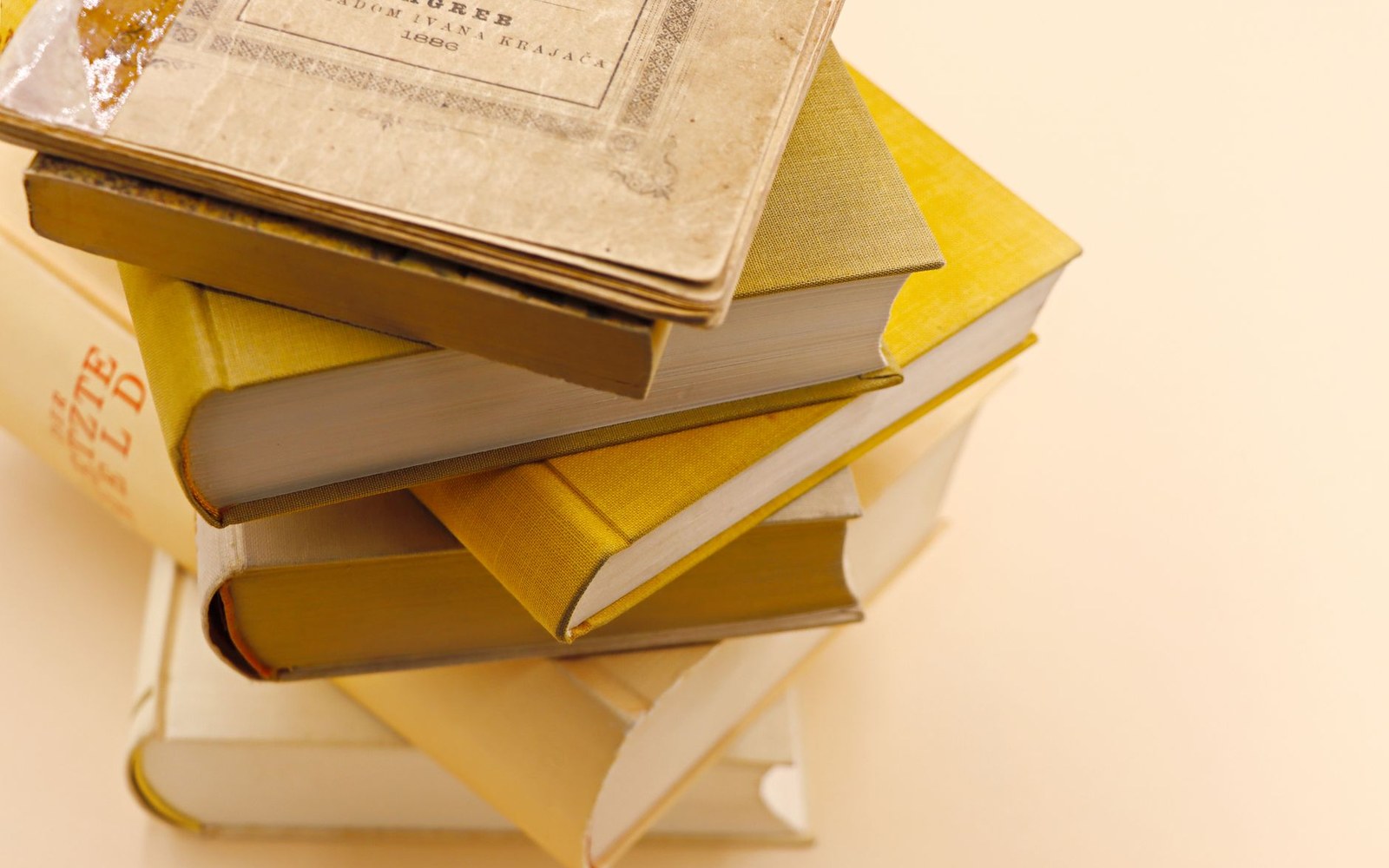 Stack of yellow hardcover books topped with a worn, aged notebook
