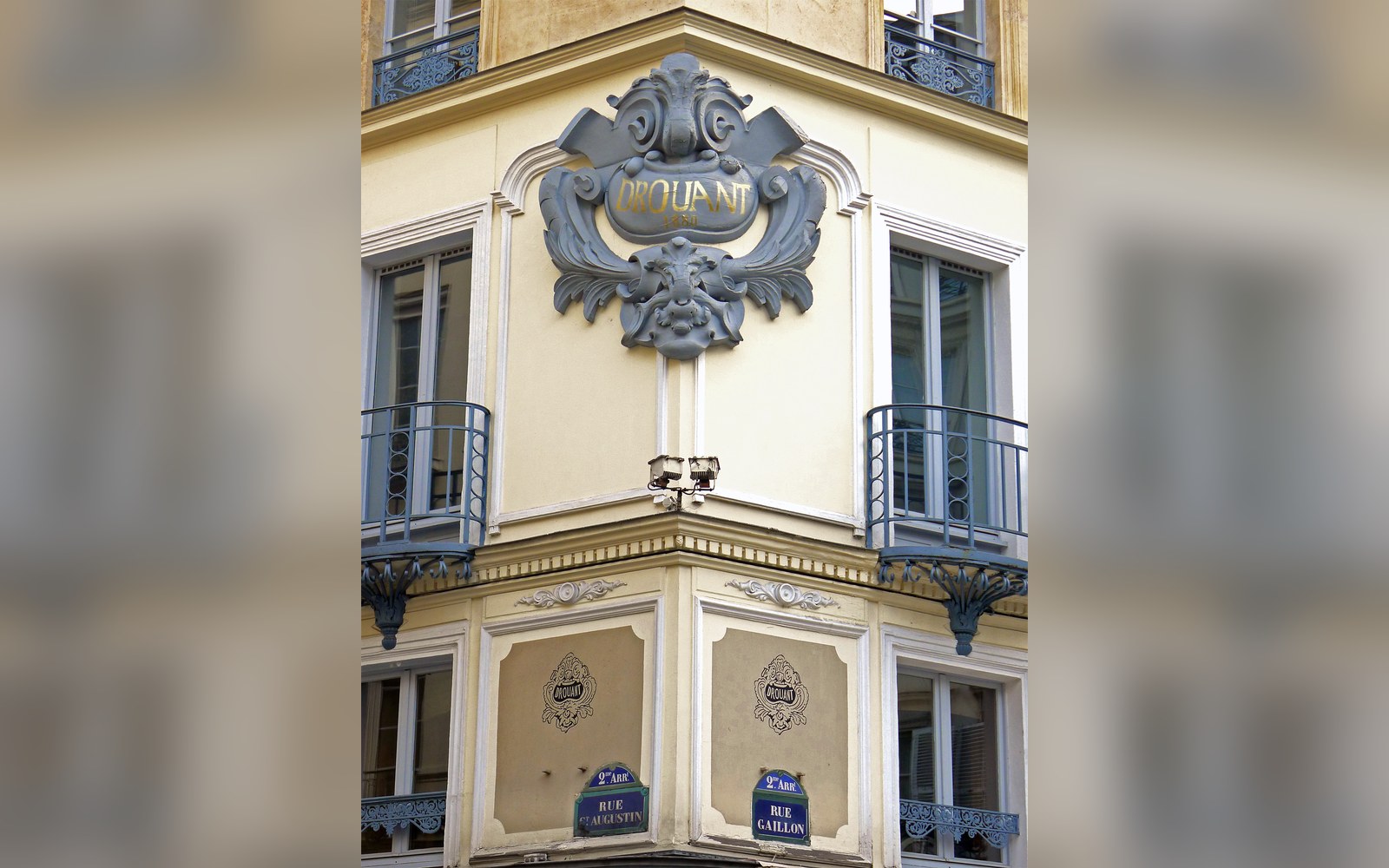 Ornate corner facade with wrought-iron balconies above street signs for Rue Gaillon